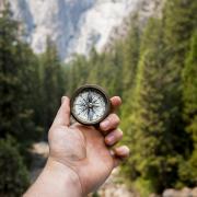 person holding compass in the mountains