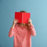 person covering face with red book