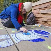 student participates in the UROP chalk drawing as part of Research & Innovation week