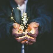 Person holding lightbulb with a string of LED lights