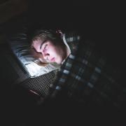 Person lying in bed in the dark looking at phone