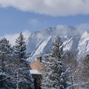 Snowy trees and mountains frame the top of a campus building