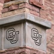 A stone column engraved with a CU symbol.