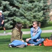 Students sit on grass at Norlin Quad