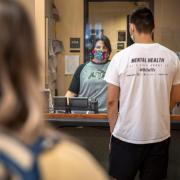 Staff member wearing a mask helps a student on campus