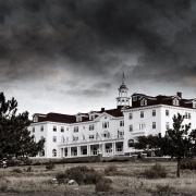 A black and white photo of the Stanley Hotel in Estes Park Colorado, with ominous black clouds in the background.
