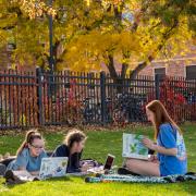 Students sit in the grass on campus