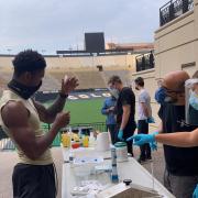 CU Boulder athlete holds up a vial for testing his saliva for the coronavirus.