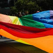 people hold large rainbow tarp outside