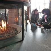 Students warm themselves on an extremely cold day at the WeatherTech Cafe fireplace 