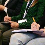 Attendees listen in and take notes during a speaker session