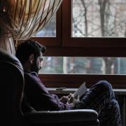 Person reads a book sitting next to a window