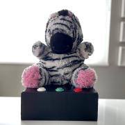 A stuffed zebra toy sits on a box with buttons