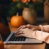 person on laptop surrounded by fall decor