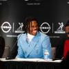 Travis Hunter sits at a table, smiling and wearing a powder blue suit.
