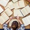 Woman seen from above looks down at books strewn across a table