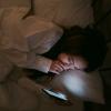 person lying in bed looking at phone