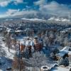 Drone shot of Old Main with the Flatirons in the background on a snowy day