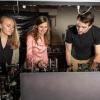 Three people stand at a scientific bench working on equipment