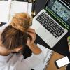 Woman with hands on head by computer.