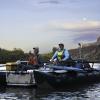 Two researchers sit on a boat with equipment.