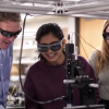 A man and two women examine scientific equipment in a lab