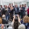 Platform guests and dignitaries watch Gov. Jared Polis celebrate after cutting a ribbon to signify the opening of the Quantum Incubator site