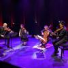The Takács Quartet performs on stage with their intruments