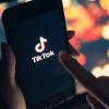 Finger touches smartphone screen displaying the TikTok logo