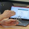 person holding a 3D model with laptop nearby