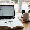 desk with laptop, notebook and cup of coffee