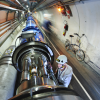 Man wearing hard hat works in a long tunnel with machinery running lengthwise