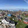 Sweeping views of Ilulissat, Greenland, show colorful buildings and many icebergs.