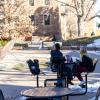 students sit at a table outside as snow melts around them