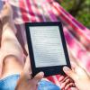 person reading on a Kindle device while relaxing in a hammock
