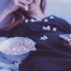 Watching TV and eating popcorn.