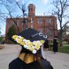 CU graduate in regalia in front of Old Main