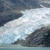 Photo of a glacier flowing through a rocky canyon into the water