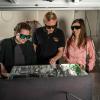 Graduate students Sara Moore and Greg Krueper with Professor Juliet Gopinath wear safety goggles and look at a large box containing technology. .