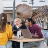 Students confer at the SEEC building lobby in front of a triceratops fossil reproduction