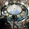 Two people walk in front of giant scientific device