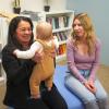 Gracia Deras sits with a mom and holds her baby.