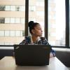 Employee sitting in front of a computer, looking out the window.