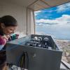 Woman looks at mechanical device with mountain view seen in background