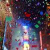 Confetti floats in the air with bright city lights in the background