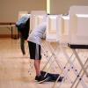 Two people stand at separate voting booths. (Glenn Asakawa/University of Colorado Boulder)