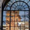 A reflection of Old Main in an arched window on campus.