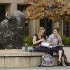 Students sit and chat near buffalo statue on campus