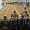 Campus community members work out on ellipticals while watching others play basketball