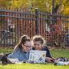 two students working at a laptop together outside
